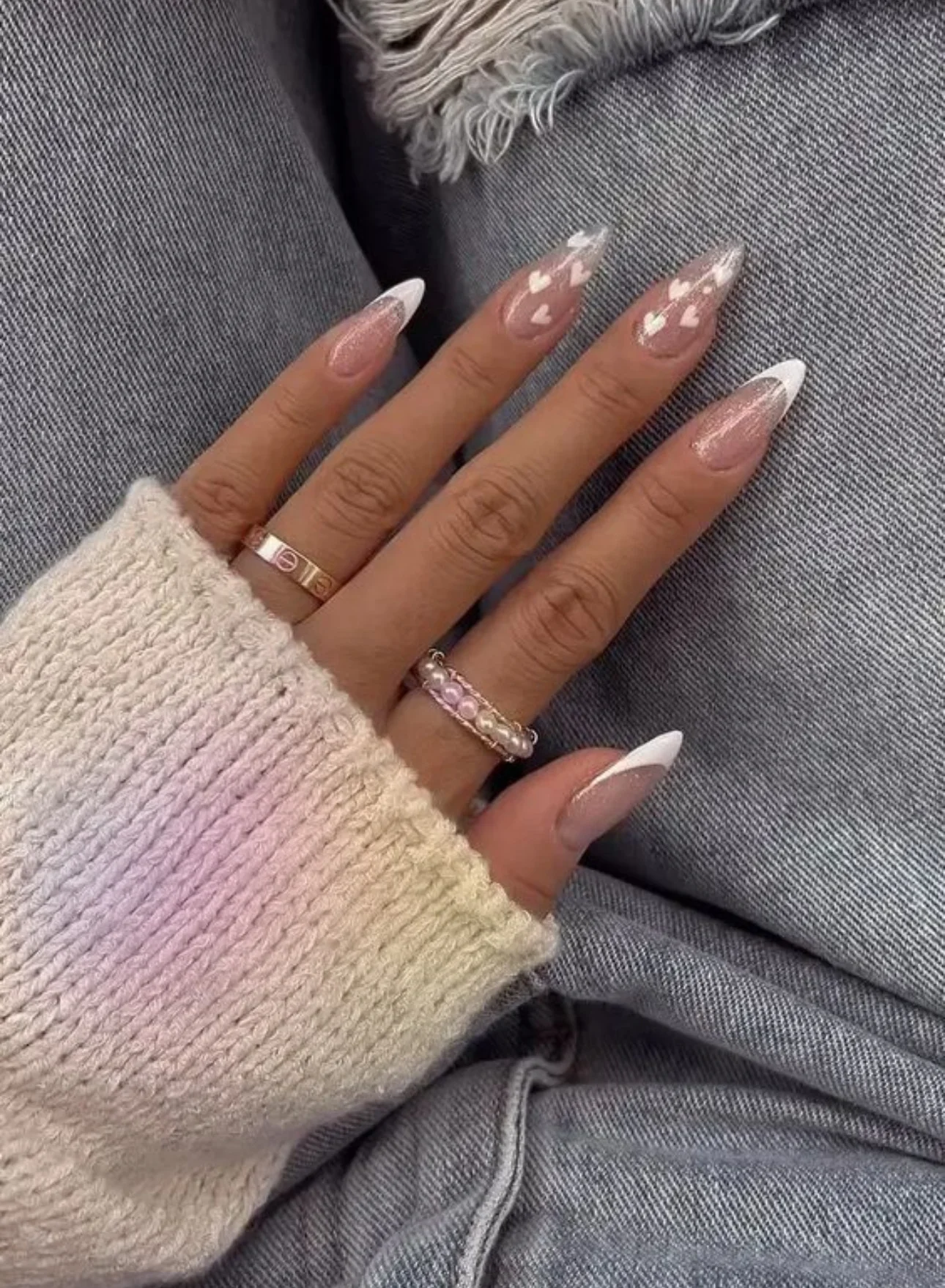 Close-up of a hand with long almond-shaped nails featuring pink glitter base, white French tips, and heart nail art design – Beverly Nails and Beauty Vaughan manicure